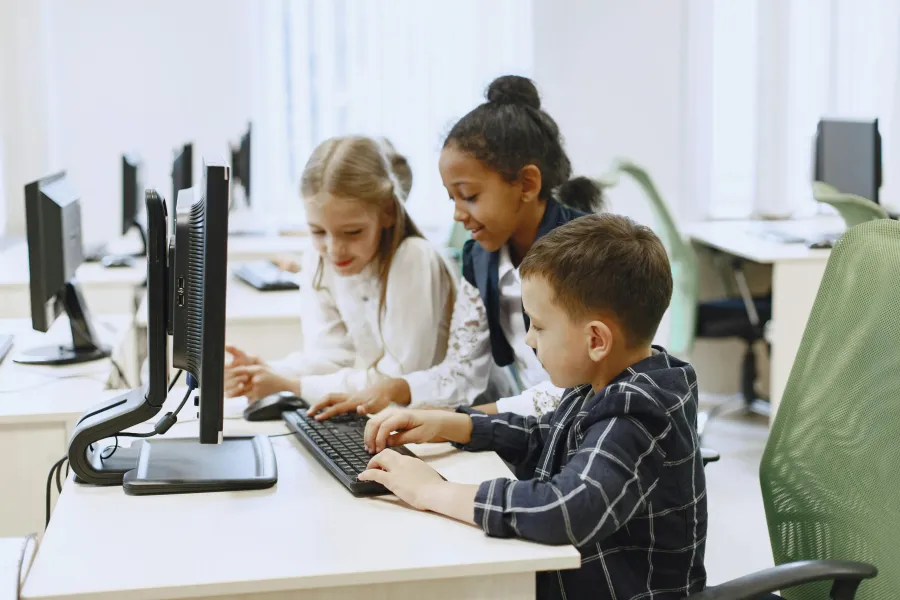Children using computers in a classroom, collaborating together.