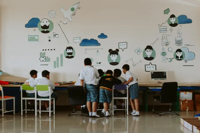 School children gathered around computer in a classroom setting.