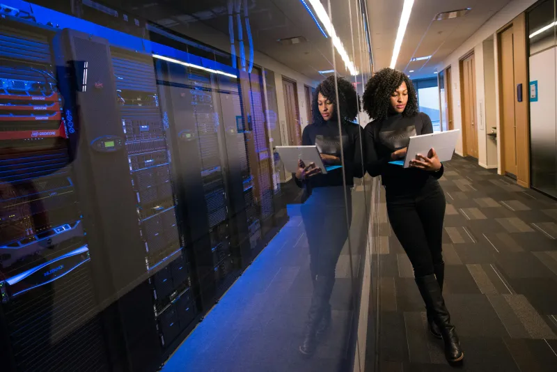Engineer reading a laptop in server room.